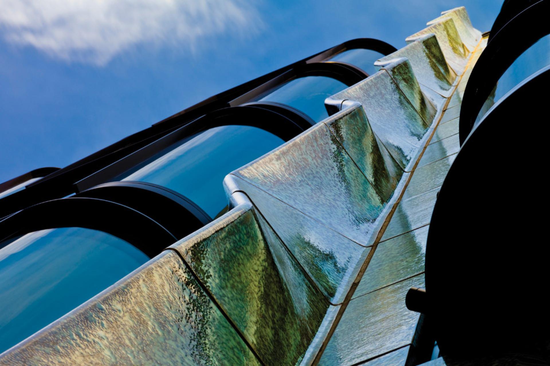 Modern architectural details showcasing iridescent materials against a clear blue sky, highlighting innovative design elements.