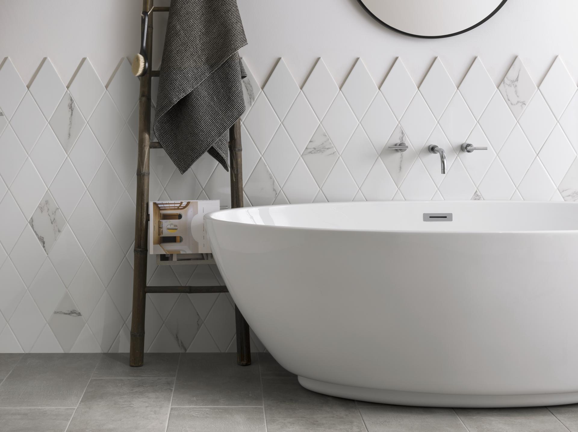 Elegant bathroom featuring a modern white freestanding tub, chic diamond-patterned tiles, and stylish towel ladder.