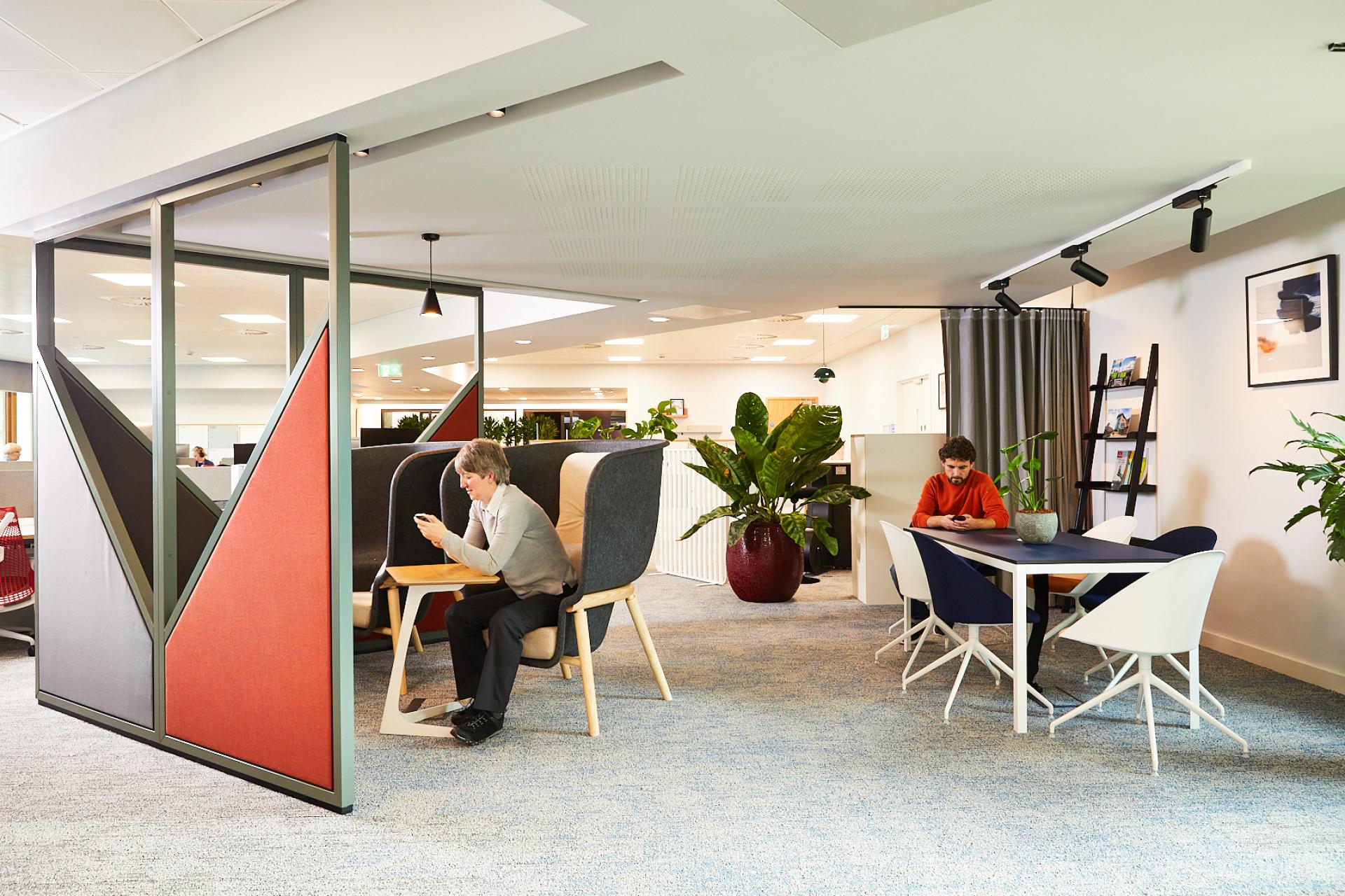 Contemporary office space featuring creative seating, greenery, and professionals engaged in collaborative work, highlighting innovative design.