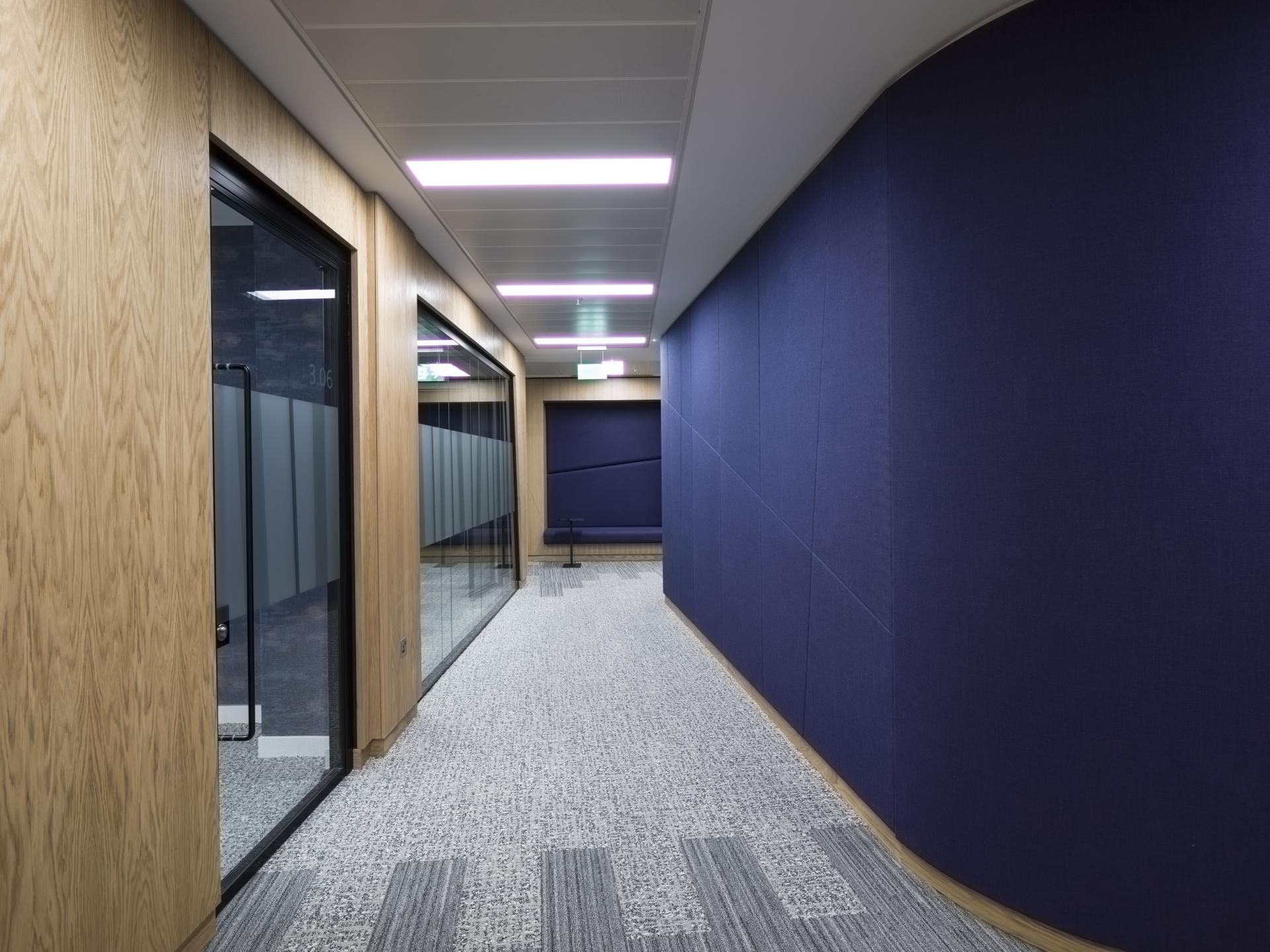 Modern office hallway featuring wood accents and acoustic panels, part of Scotland's first WELL certified workspace.