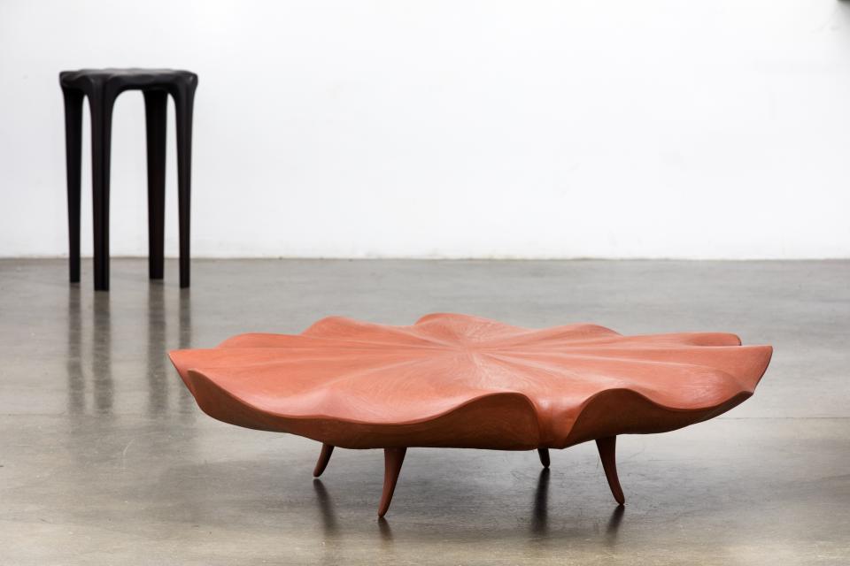 A sculptural coffee table in a petal shape with wooden legs, showcasing innovative furniture design by Christopher Kurtz.