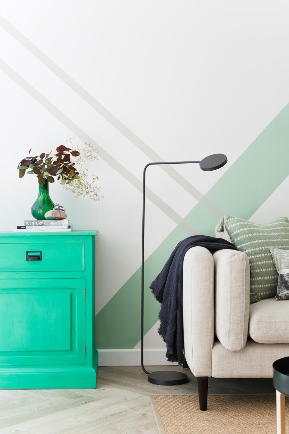 Contemporary Scandi Industrial living room featuring a vibrant green cabinet, stylish lamp, and cozy sofa accents.