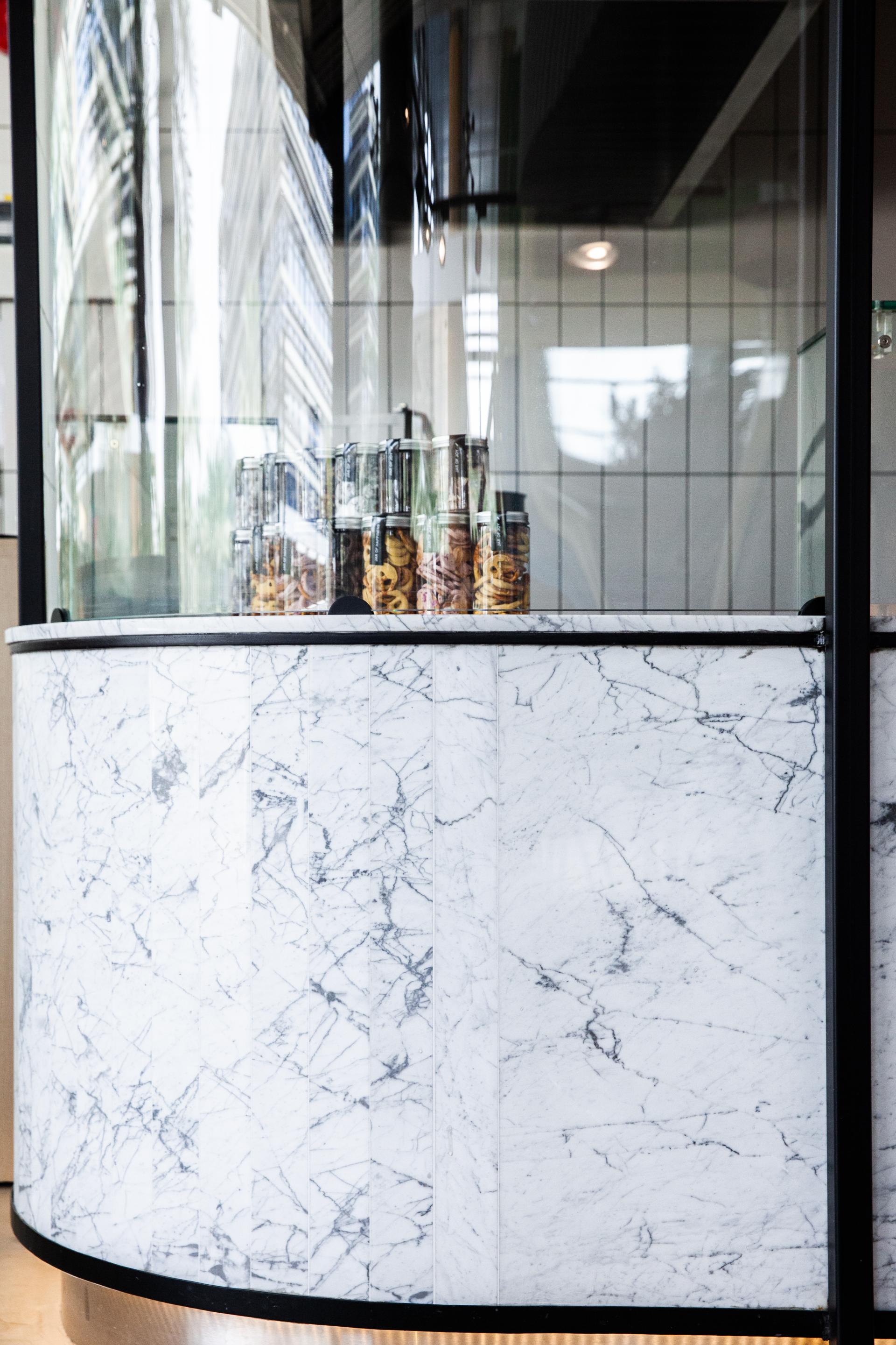 Elegant marble counter showcasing jars of desserts at a stylish Chunk café location designed by H2R DESIGN in Riyadh.