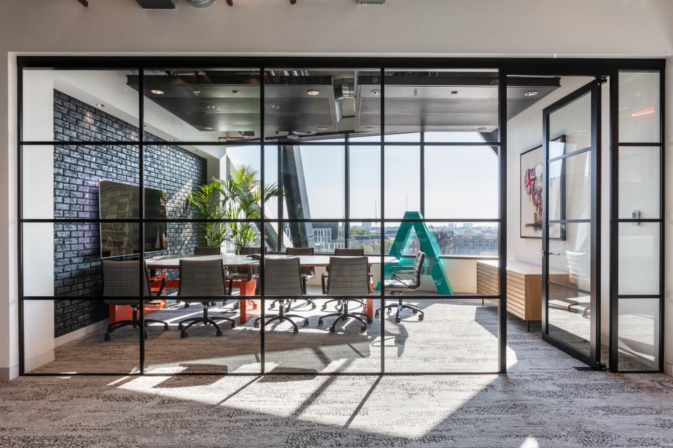 Modern office space featuring a glass conference room with stylish furniture, greenery, and a vibrant design for Alpha FX London.