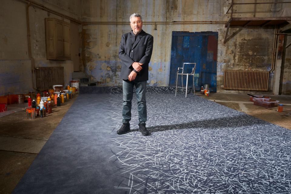 Philippe Starck stands in a creative space showcasing the Flotex By Starck flooring collection by Forbo.