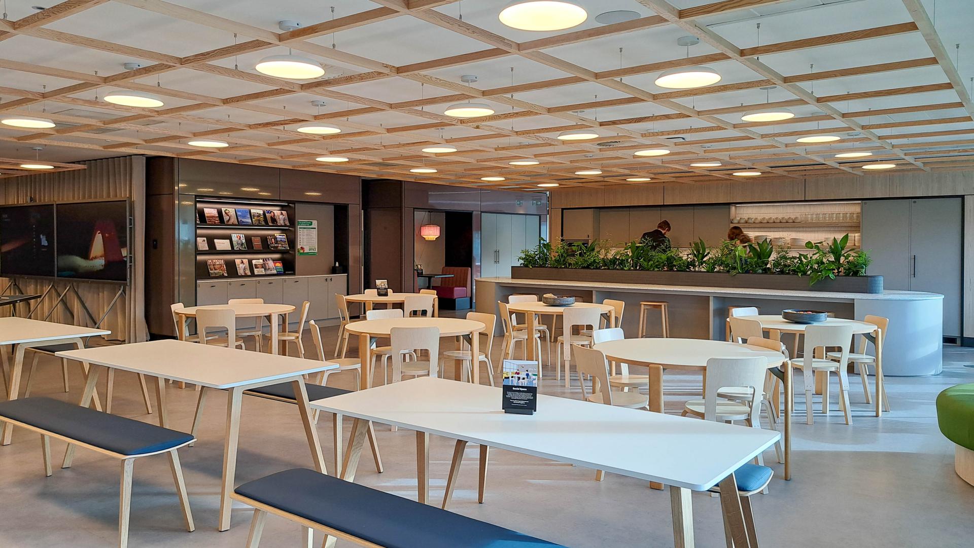 Modern workspace featuring tables and greenery, designed to enhance collaboration for FinTech firms like Conferma.
