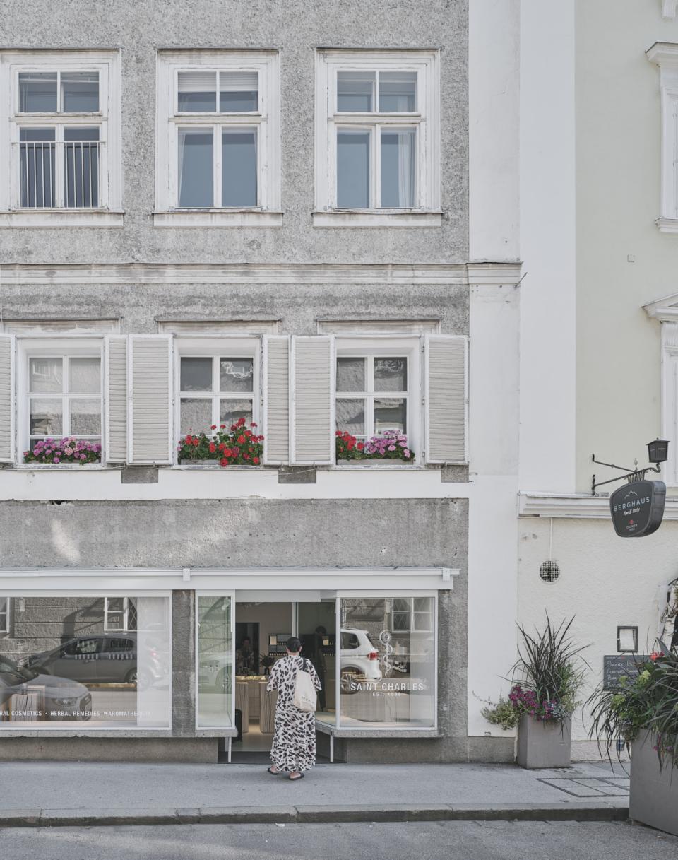 Saint Charles natural cosmetics store in Salzburg features a welcoming entrance and vibrant flower boxes above.