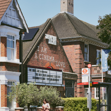 Refurbished exterior of The Lexi cinema, featuring a marquee with film listings and a woman walking past.