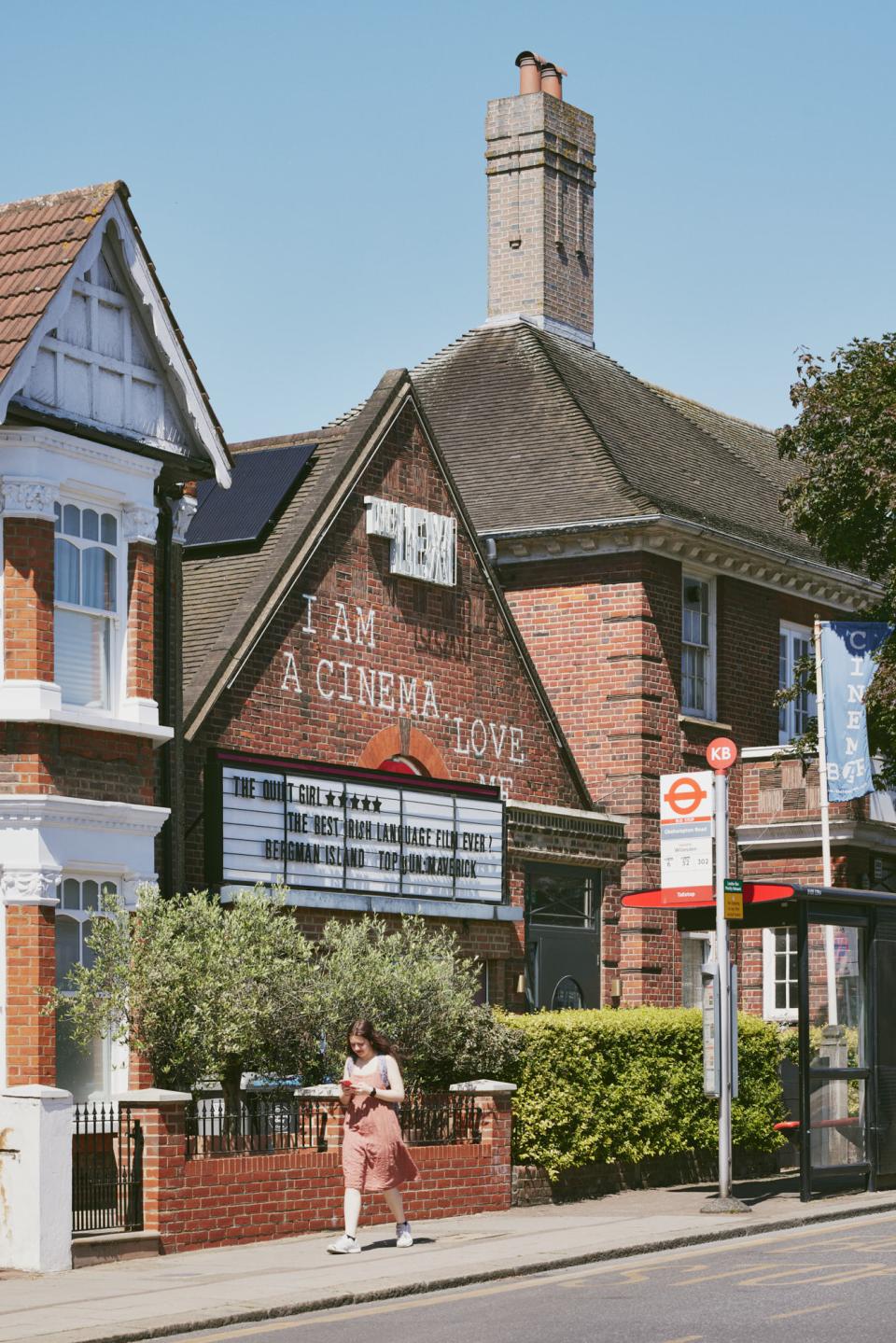 Refurbished exterior of The Lexi cinema, featuring a marquee with film listings and a woman walking past.