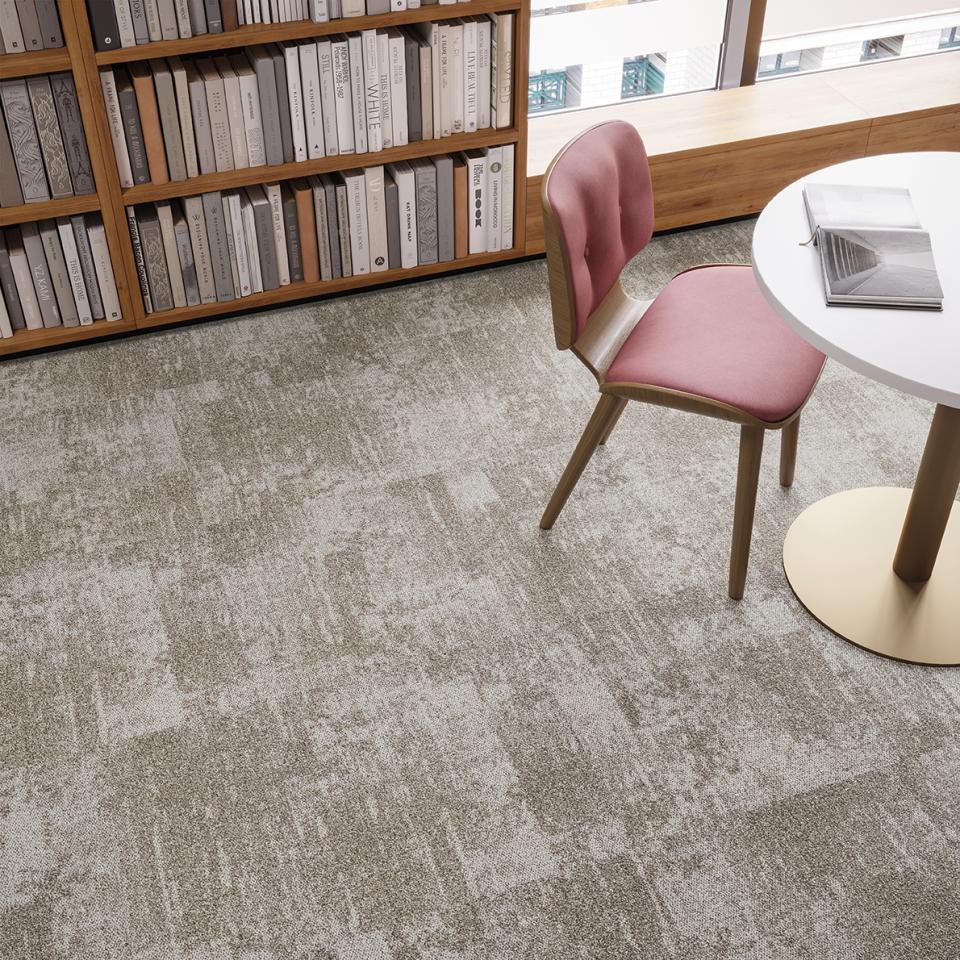 Tessera Infused carpet tiles enhance a modern workspace, featuring a stylish pink chair and clean design elements.