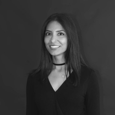 Vidhi Sharma, Creative Director at Modus, smiles confidently against a dark backdrop, embodying creativity and professionalism in her workspace.