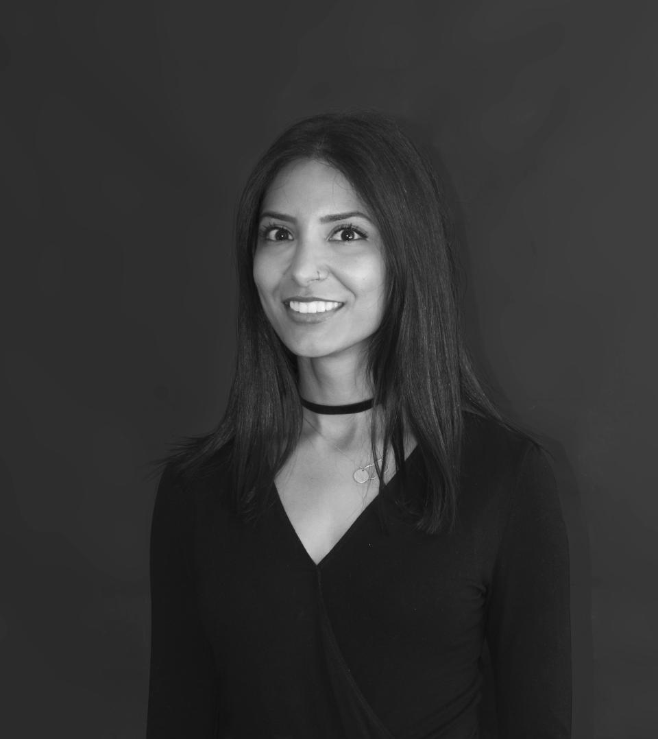 Vidhi Sharma, Creative Director at Modus, smiles confidently against a dark backdrop, embodying creativity and professionalism in her workspace.