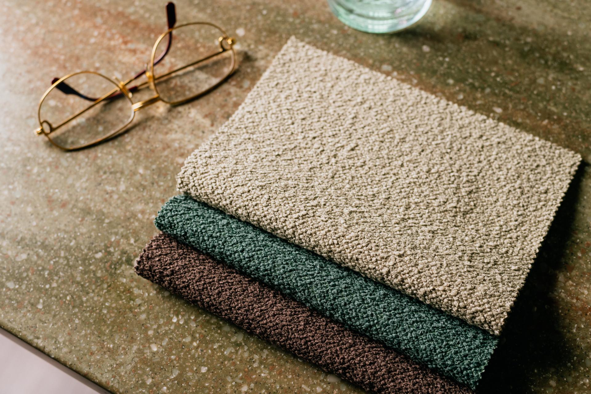 Three soft, textured upholstery fabric samples in neutral and earthy tones, showcasing Agua Fabrics' new collection for performance design.