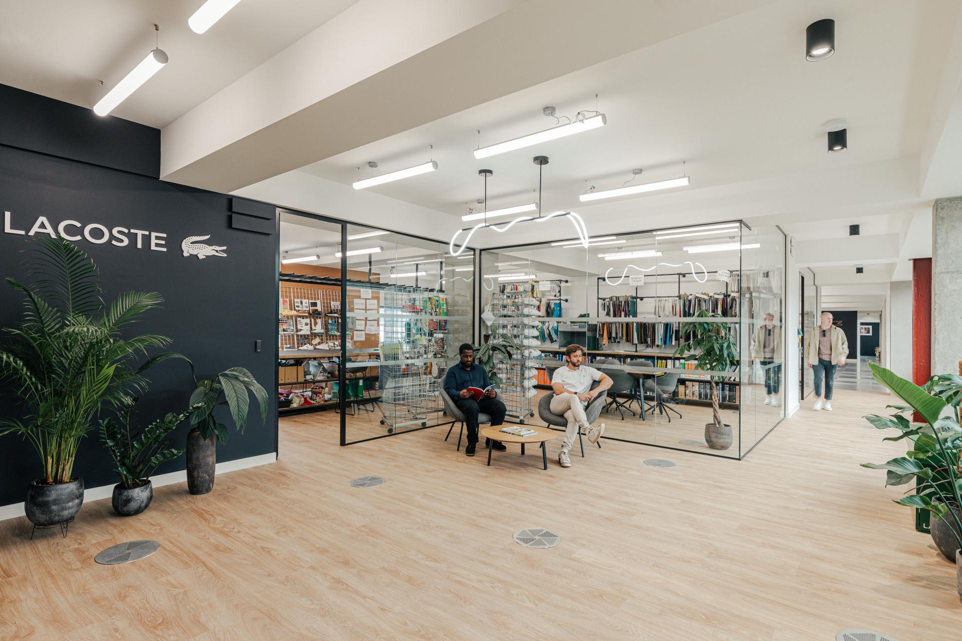 Lacoste's new London workspace features a modern design, with employees collaborating in a spacious, warehouse-inspired setting.