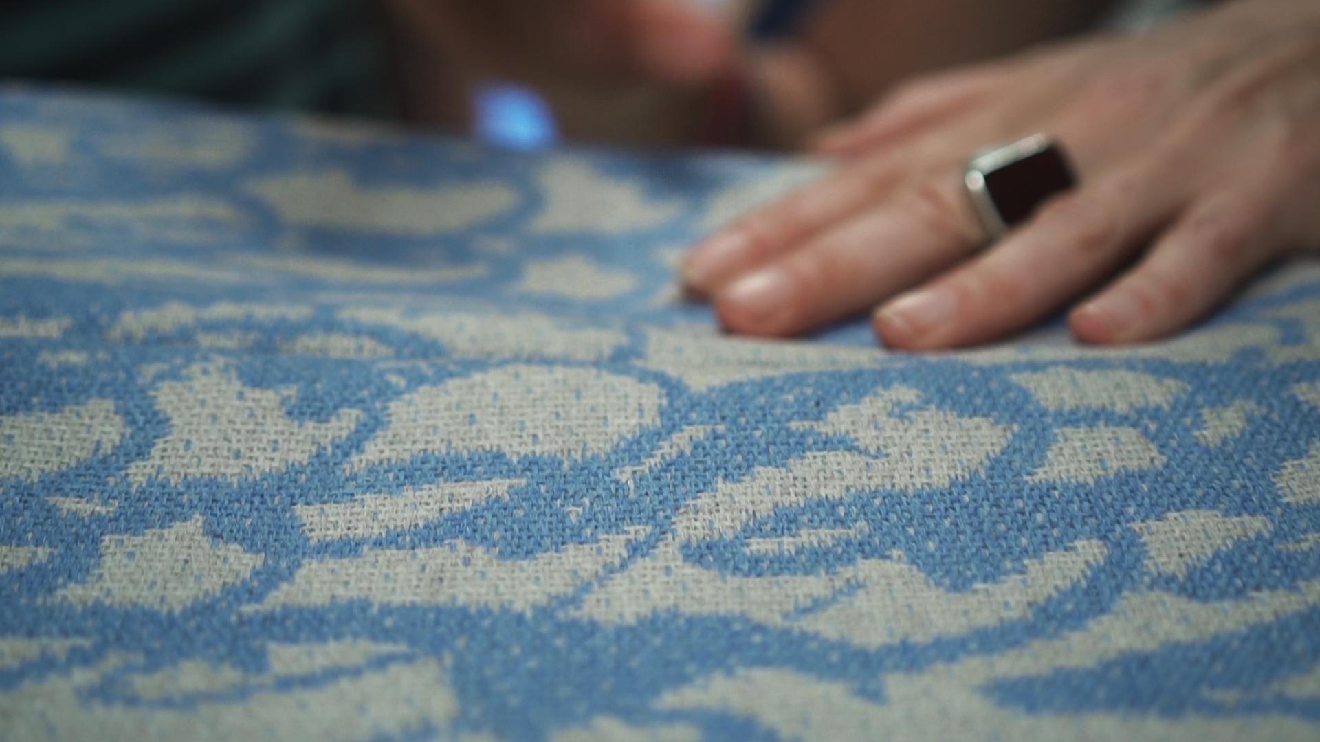 Close-up of a textured fabric featuring a blue and cream pattern, highlighting British wool craftsmanship by designer Ella Doran.