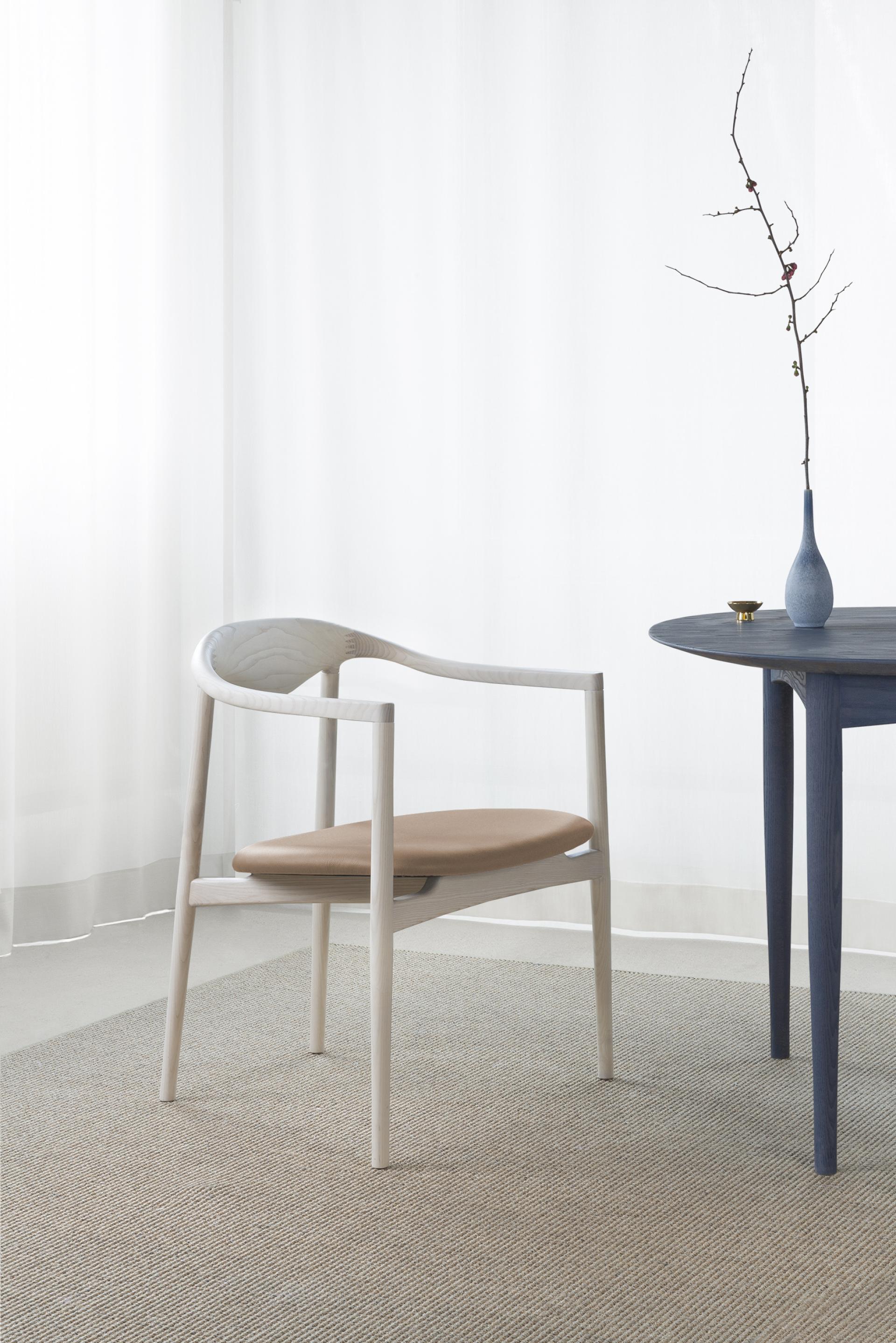 Elegant JARI dining chair by Brdr. Krüger beside a round table, showcasing modern Danish design and craftsmanship.