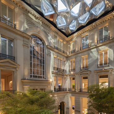 Foster + Partners' Apple Store features elegant Parisian architecture with a geometric glass ceiling and lush greenery in the courtyard.