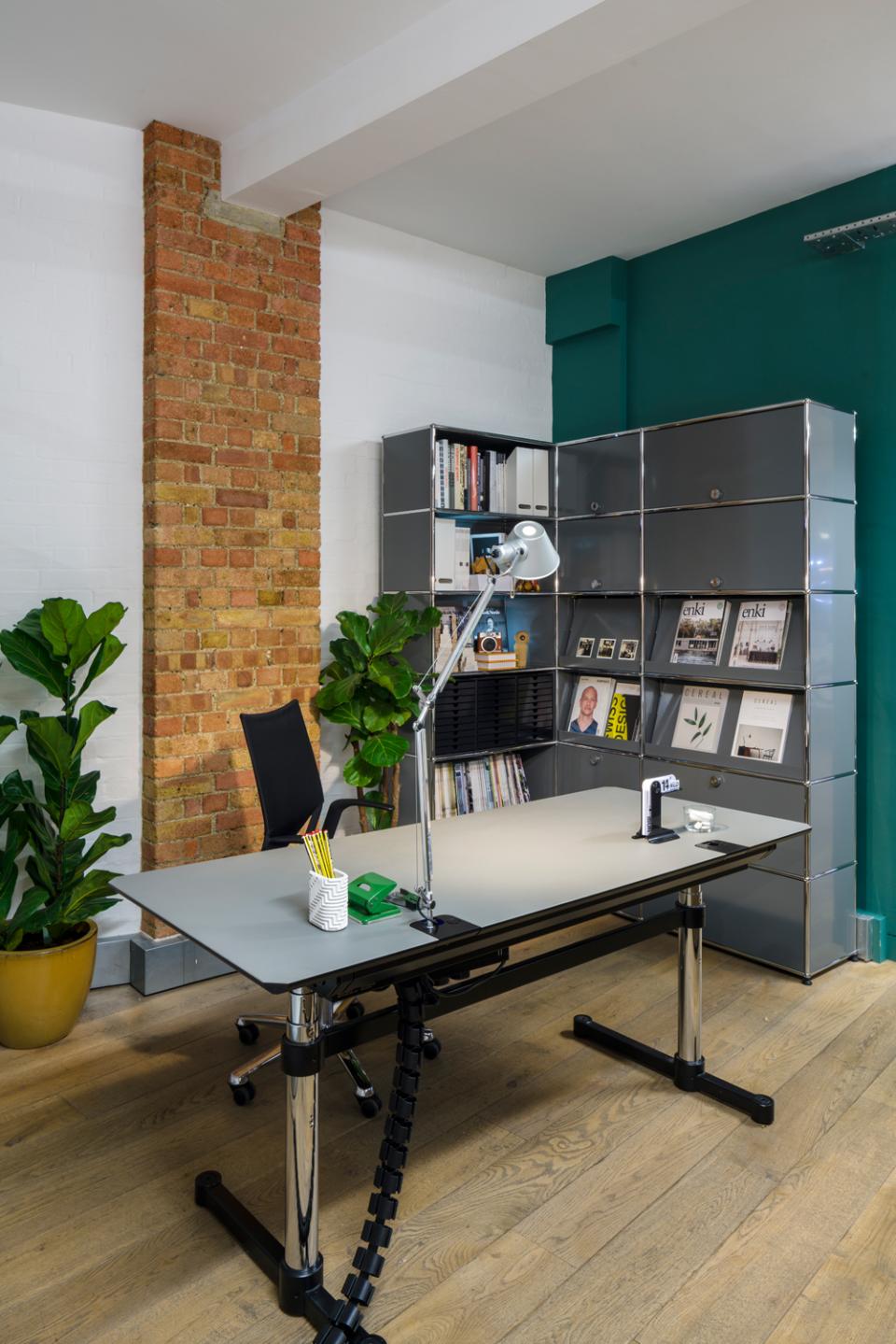 Modern office setup featuring USM modular furniture, showcasing a sleek desk, stylish shelving, and vibrant greenery.