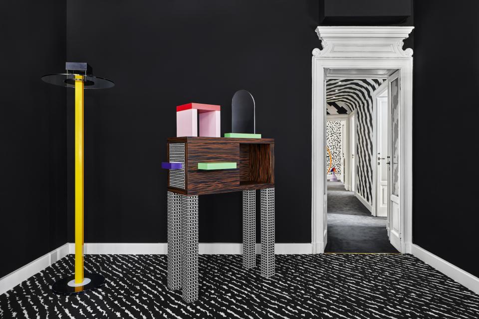 Colorful Memphis Milano furniture piece against a sleek black wall, showcasing bold design elements and playful patterns.