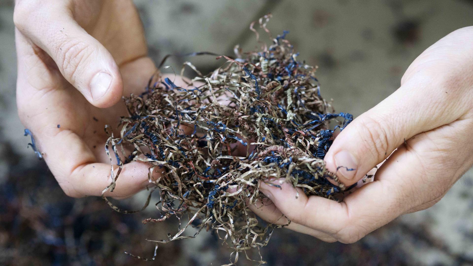 Hands holding colorful shreds of ebonite material, showcasing the innovative design process behind AJOTO's terrazzo pen rests.