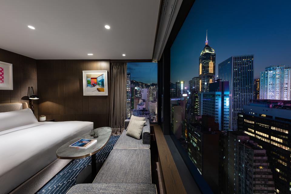 Stylish hotel room in The Hari Hong Kong showcasing stunning city skyline views at night.
