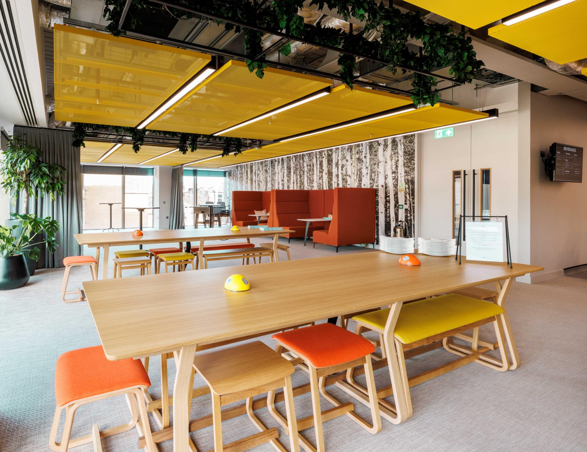 Modern office space featuring sustainable design elements, colorful furniture, and abundant natural light for collaborative work environments.