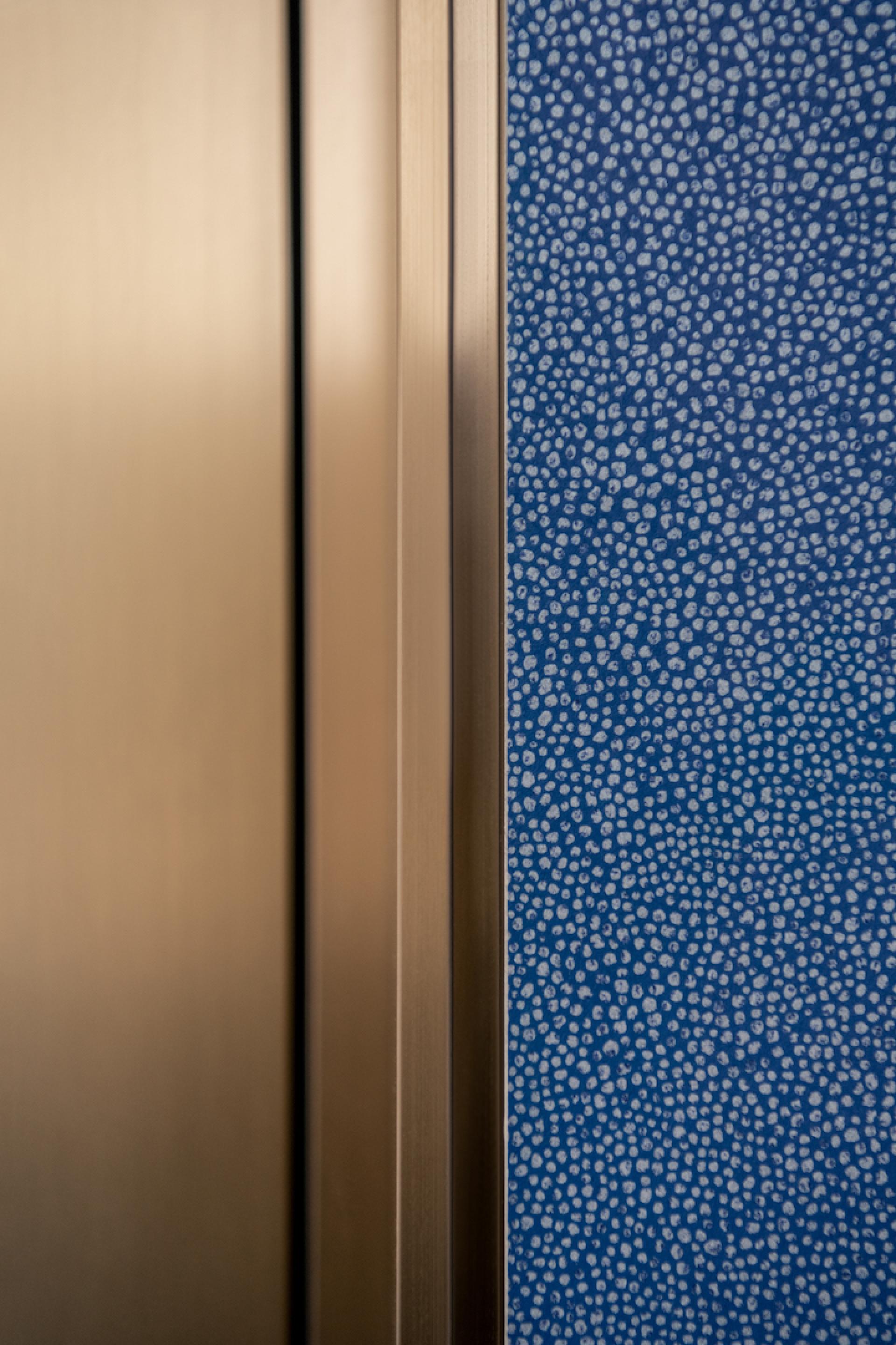 Close-up of a textured blue wall and metallic paneling in Warner Music's innovative Beijing workplace designed by Bean Buro.