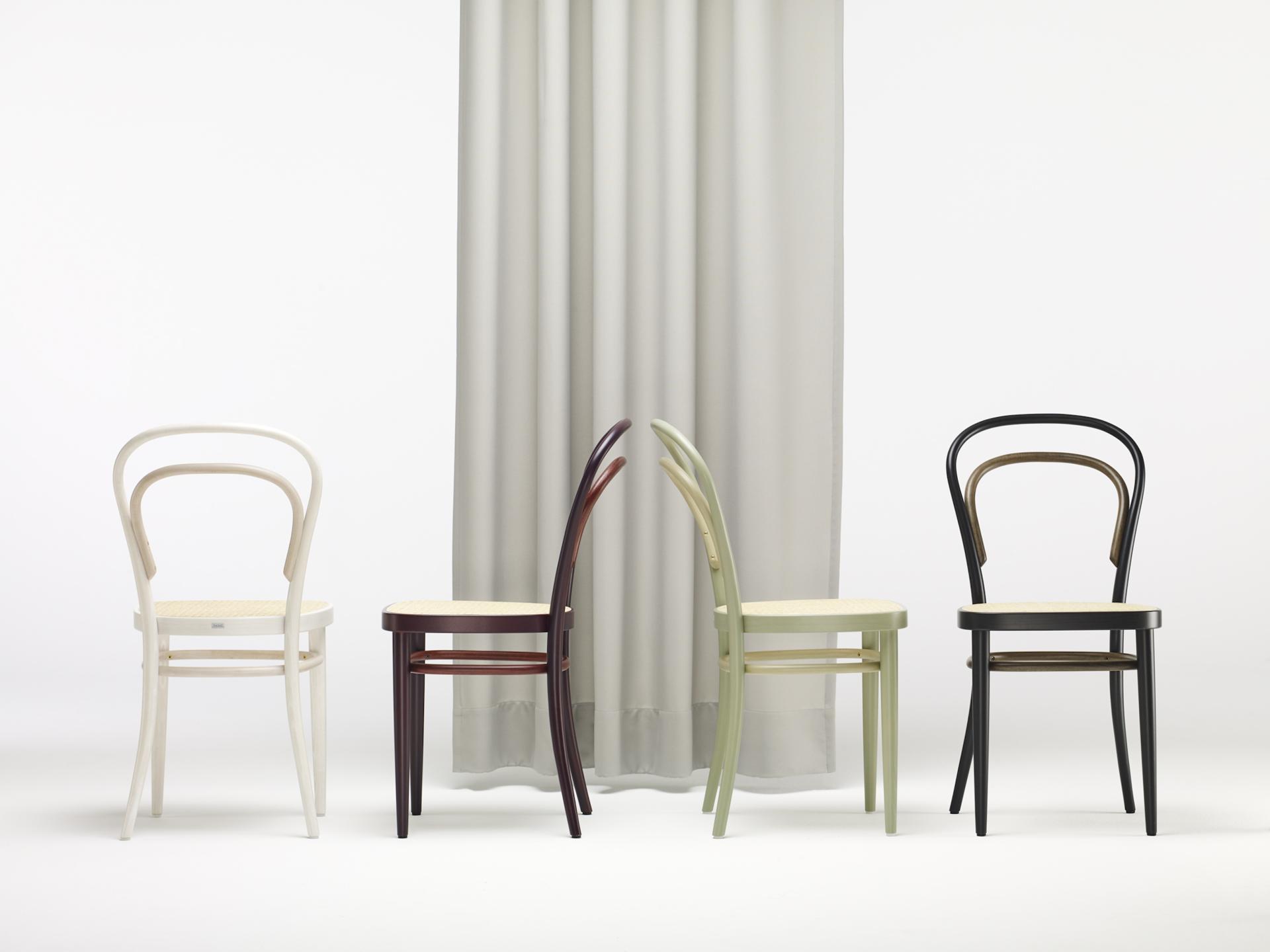 Elegant Thonet chairs in various colors stand in a row against a minimalist backdrop, symbolizing Bauhaus design heritage.