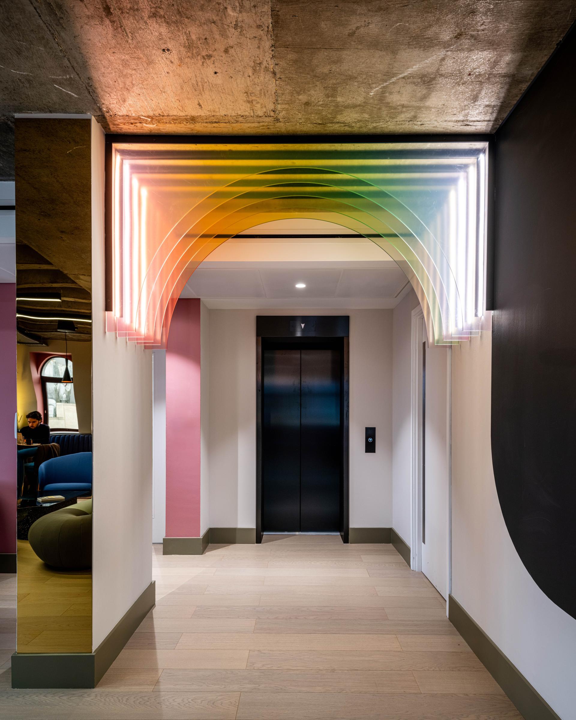 Vibrant co-working space entrance at Huckletree Kensington featuring colorful arch lighting and modern design elements.