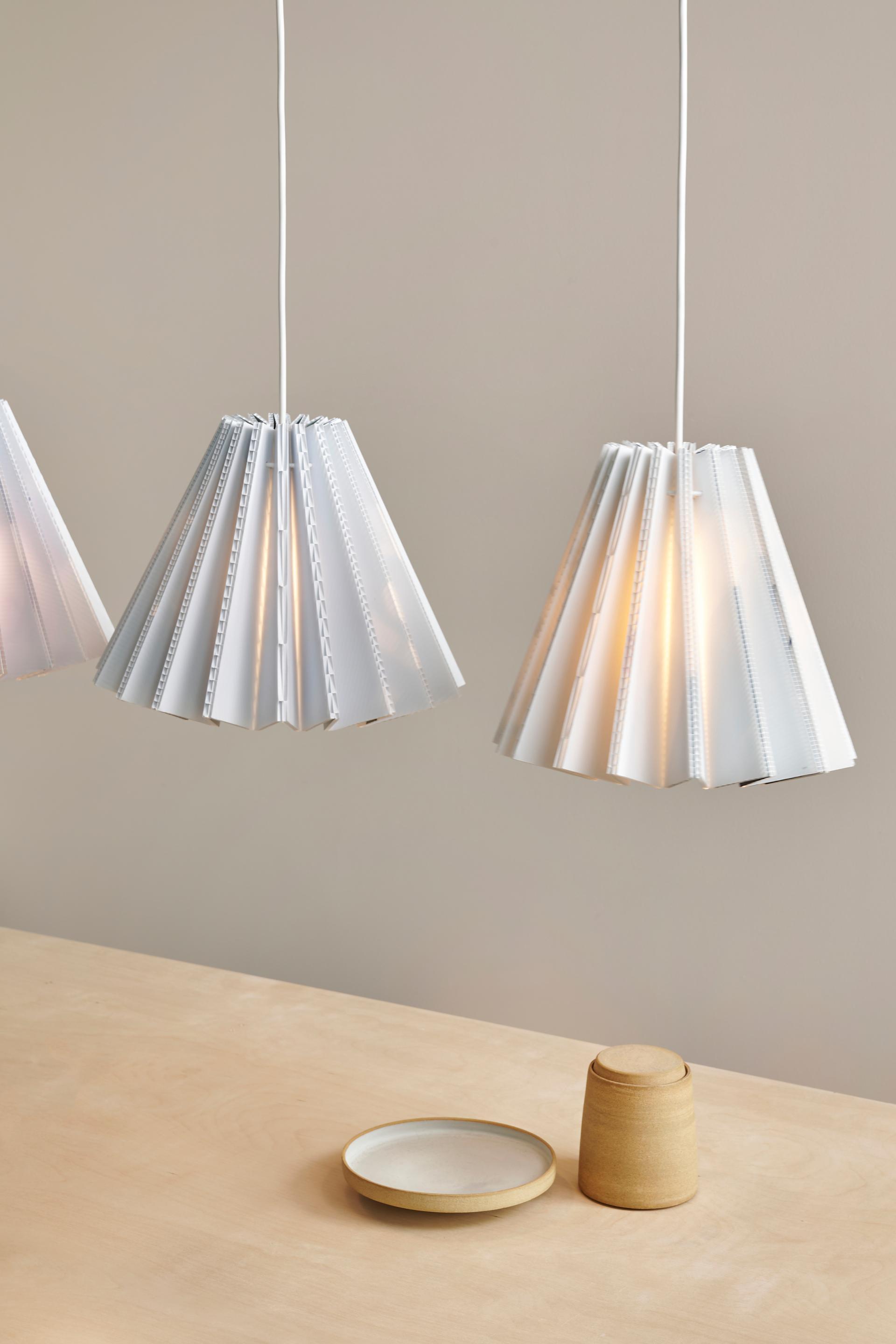 Sustainable sculptural lampshades from Tabitha Bargh's Poly collection, featuring unique folded designs and warm lighting.