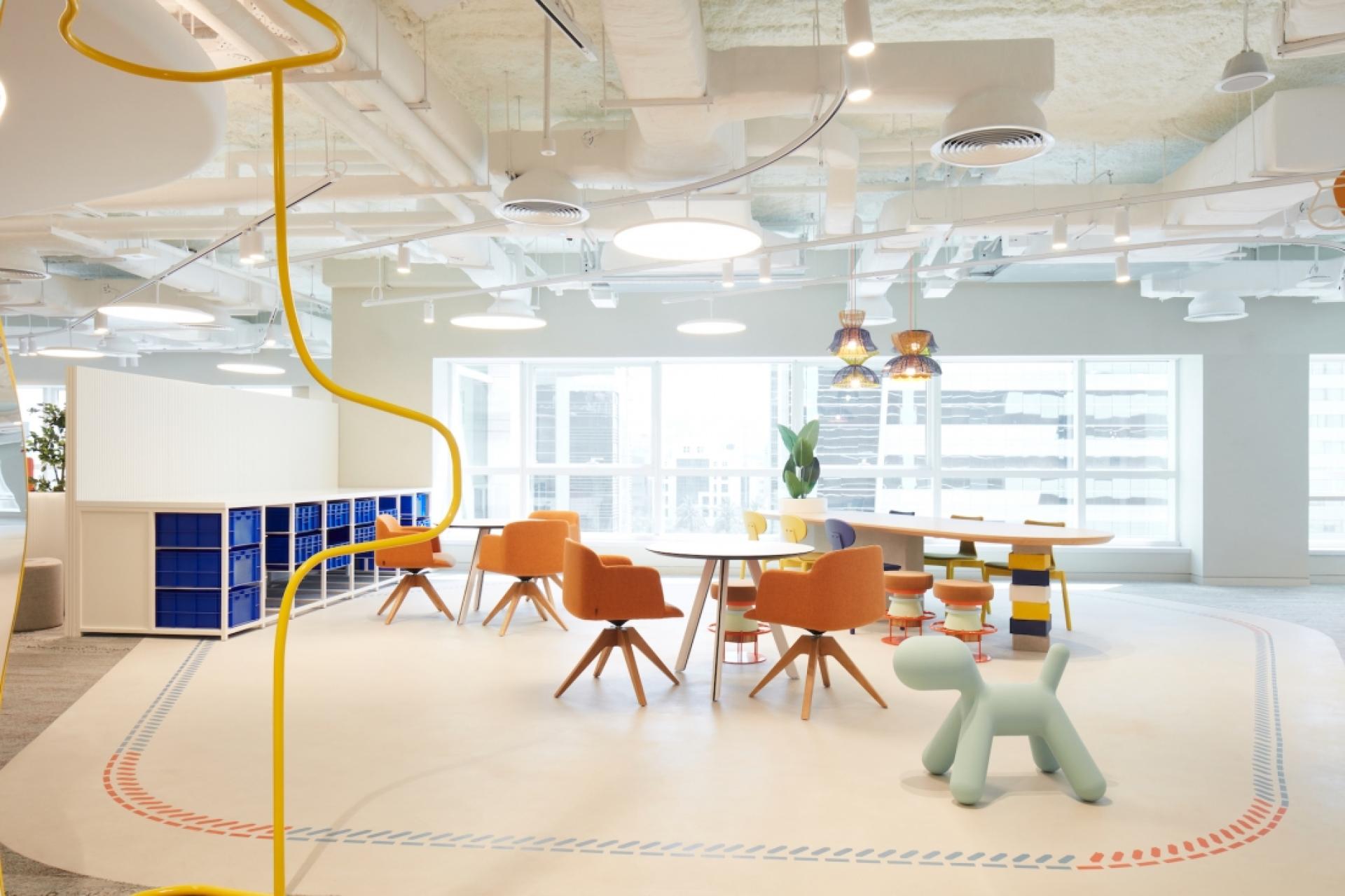 Modern office design featuring colorful furniture, collaborative workspaces, and ample natural light, promoting innovation and creativity.