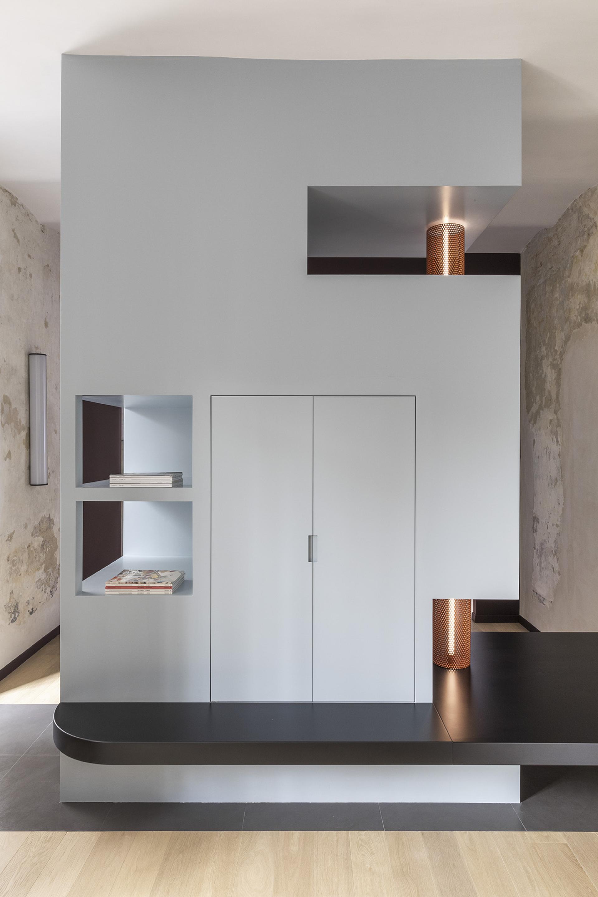 Stylish interior of a compact Trastevere apartment featuring modern shelving, a sleek entrance, and warm lighting accents.