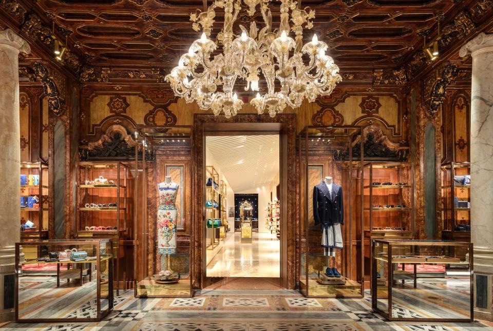 Luxurious interior of Dolce & Gabbana's Venetian flagship store featuring elegant designs, clothing displays, and an ornate chandelier.