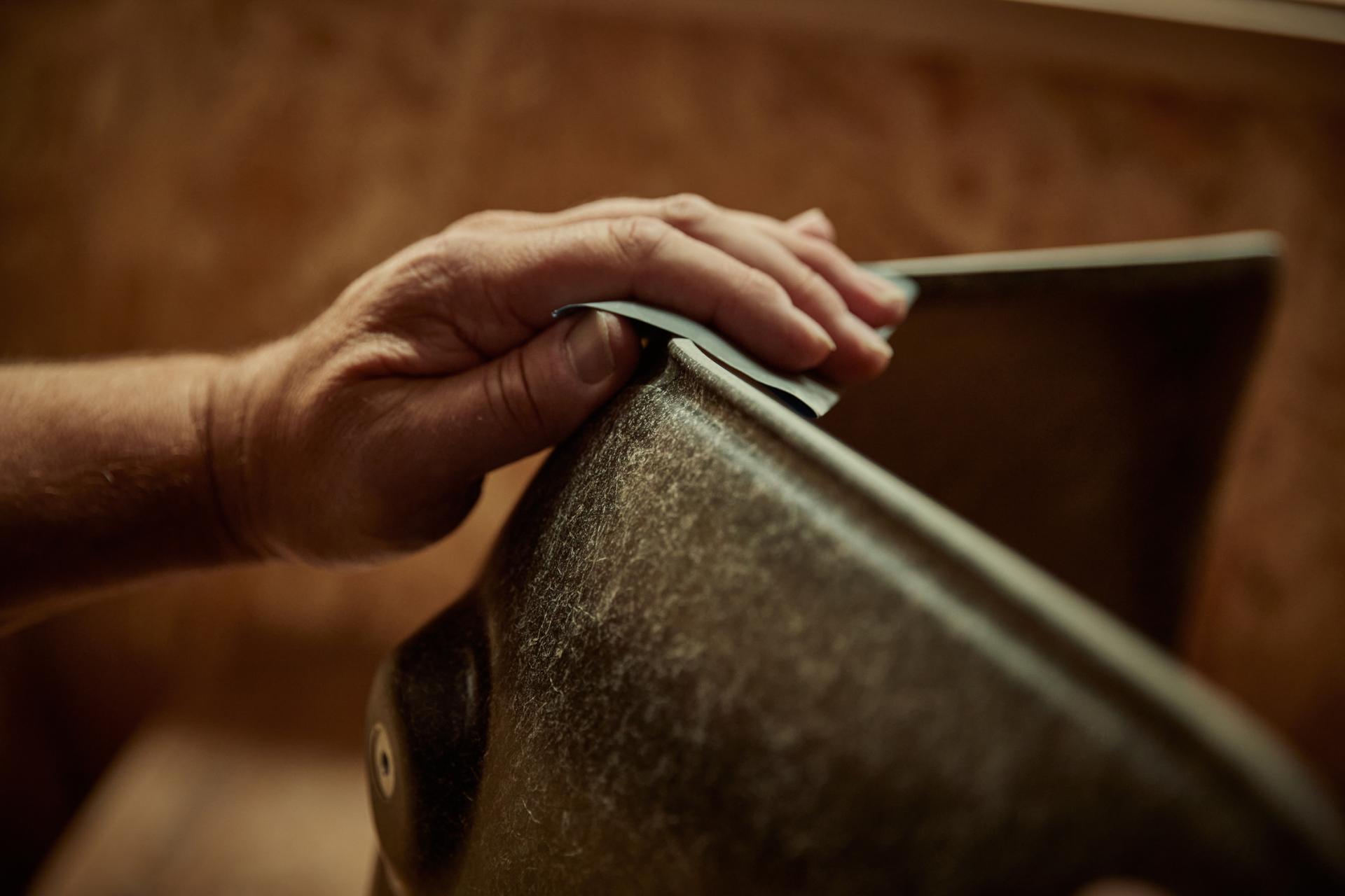 Craftsman hand smoothing solidwool furniture, showcasing sustainable British materials and skilled craftsmanship in furniture design.