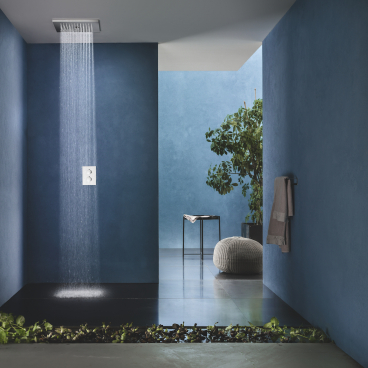 Modern bathroom featuring blue walls, a rainfall shower, and stylish decor elements, showcasing 2022 design trends.