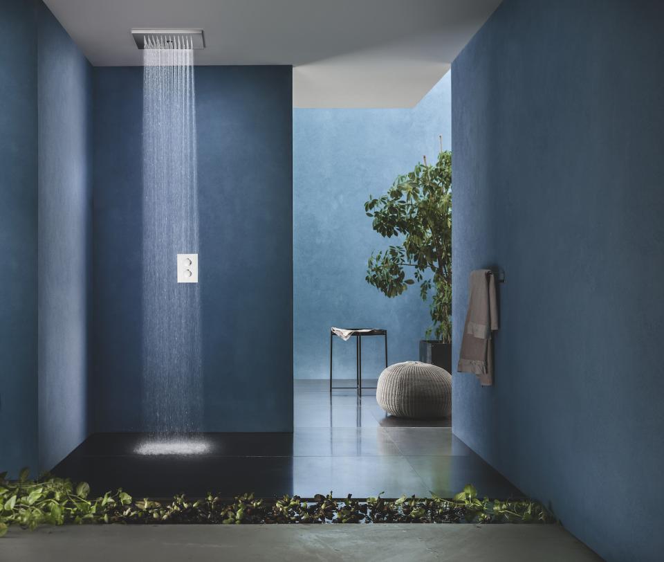 Modern bathroom featuring blue walls, a rainfall shower, and stylish decor elements, showcasing 2022 design trends.