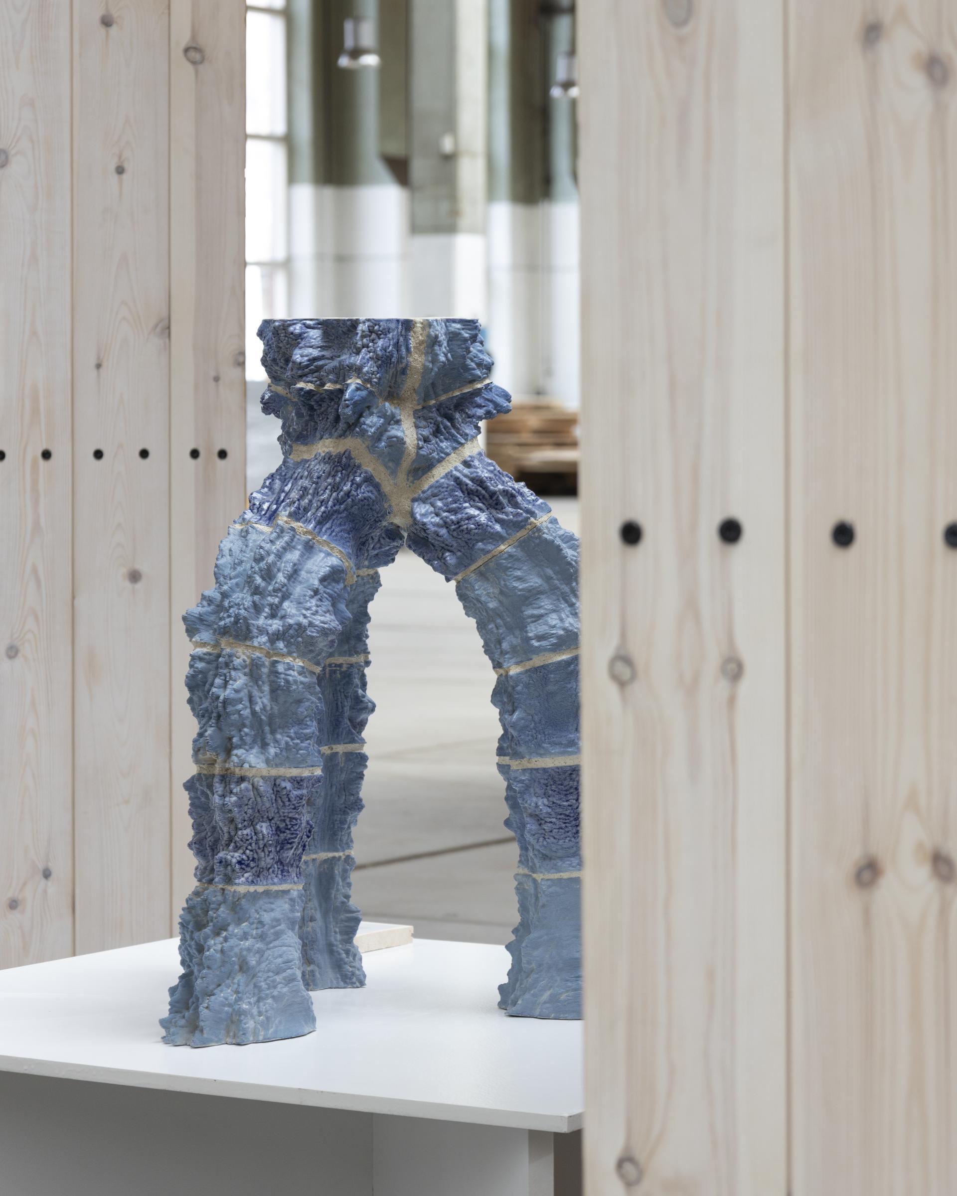 Innovative blue 3D-printed structure displayed in a minimalist gallery, showcasing advancements in construction technology.