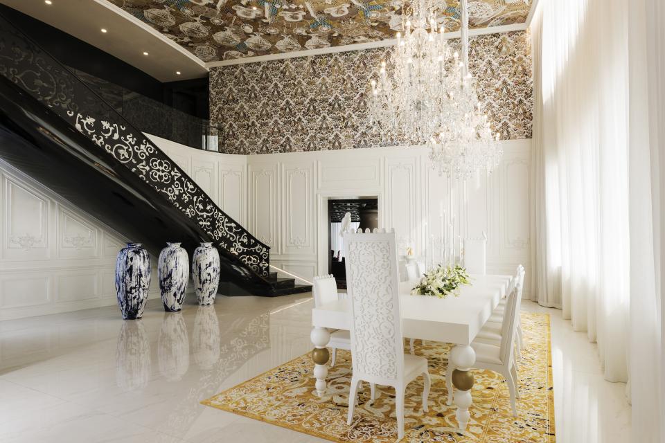 Luxurious dining area featuring intricate white furnishings, a grand chandelier, and decorative vases in the Mondrian Doha hotel.