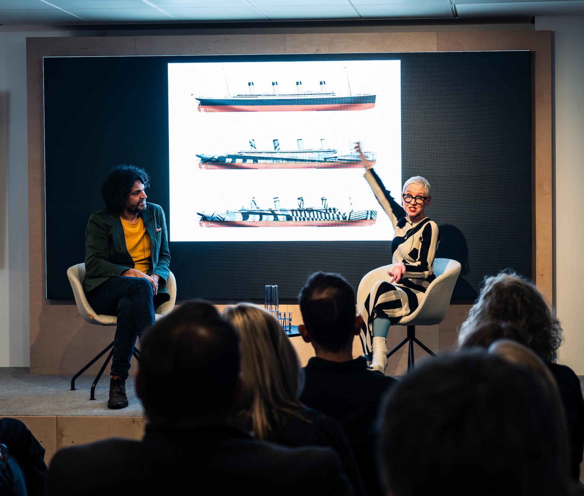 Anna Campbell-Jones presenting at Material Source Studio with a visual display of ship designs during an engaging conversation event.