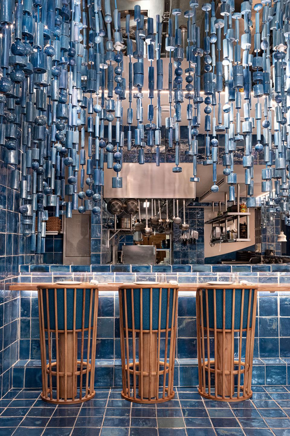 Stylish interior of La Sastrería restaurant featuring blue tiled walls and unique hanging decor, emphasizing modern design elements.