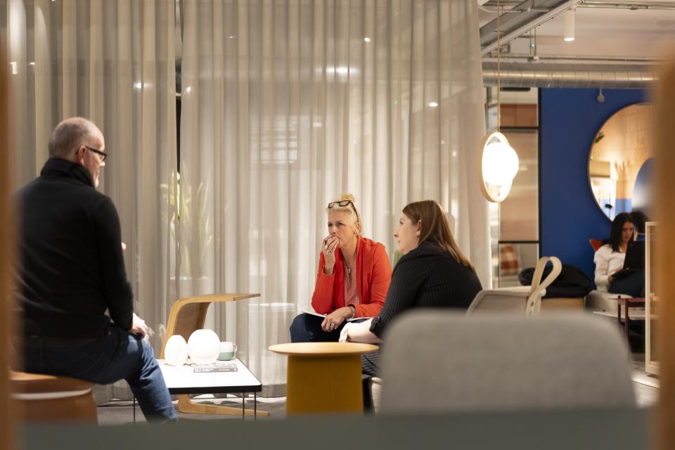 Engaged attendees converse in a modern studio setting during the third anniversary celebration at Material Source in Manchester.