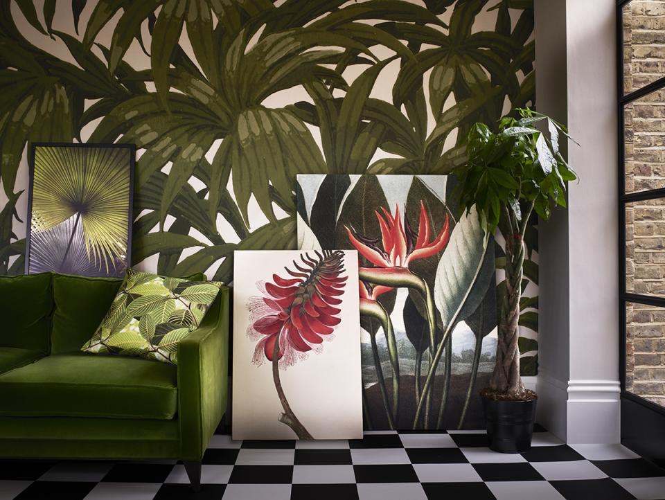 Lush greenery adorns the wall, with vibrant botanical prints and a stylish green sofa enhancing the room’s eco-friendly decor.