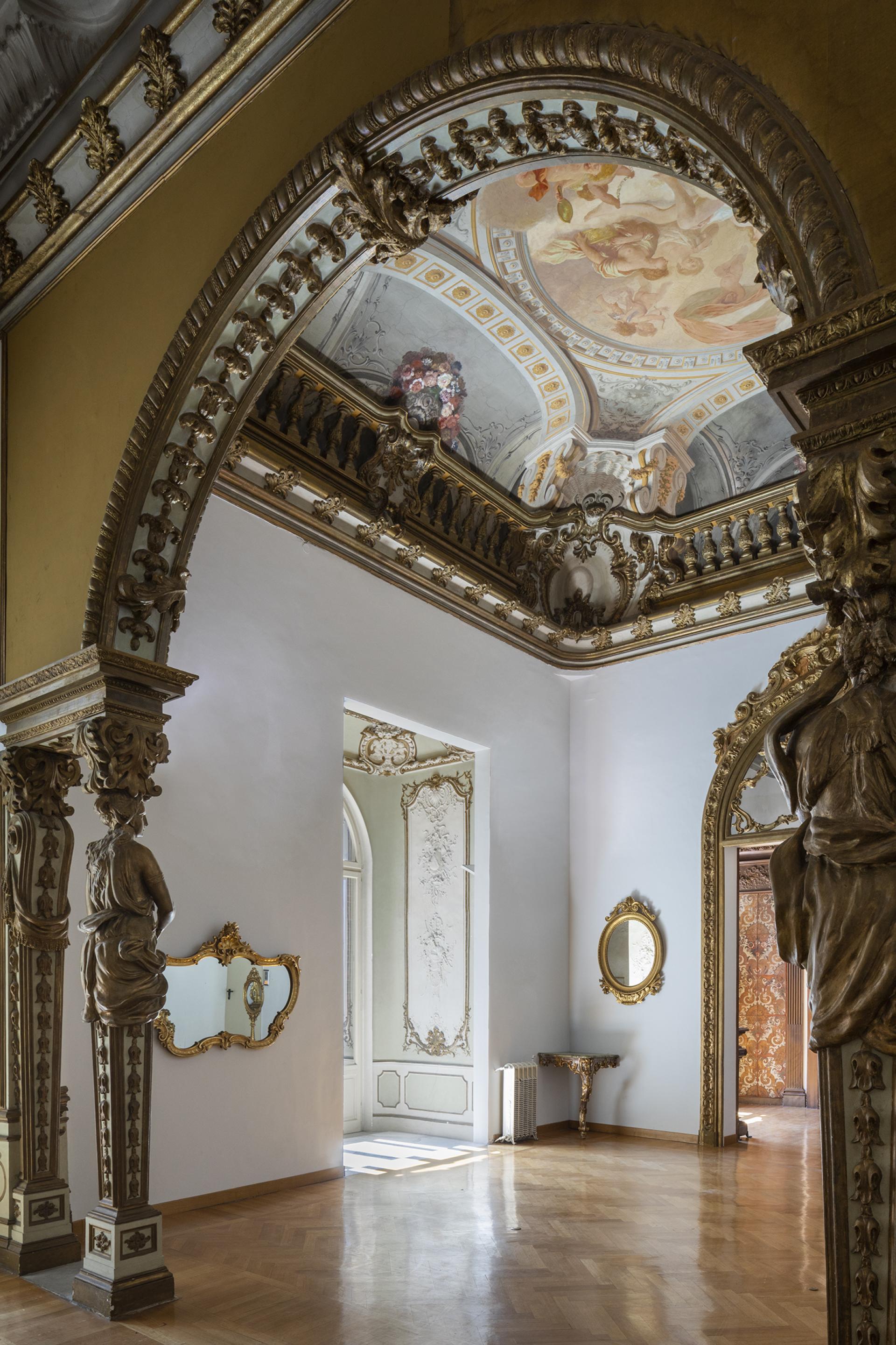 Elegant interior of Palazzo Brancaccio featuring intricate frescoes, ornate mirrors, and classic architectural details.