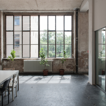 Bright, spacious interior of Lindower 22 featuring large windows, plants, and modern furnishings in an industrial setting.