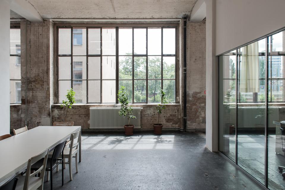 Bright, spacious interior of Lindower 22 featuring large windows, plants, and modern furnishings in an industrial setting.