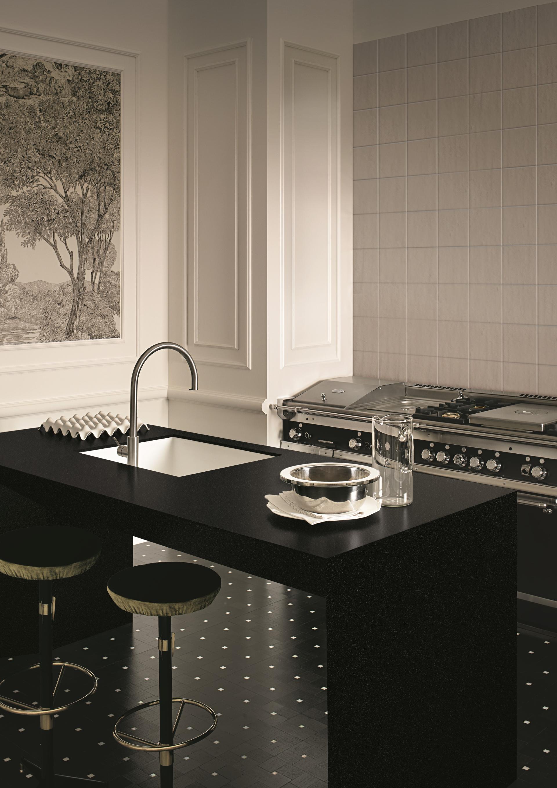 Modern kitchen featuring a sleek black countertop, stylish stools, and a high-end stove, showcasing innovative surface trends.