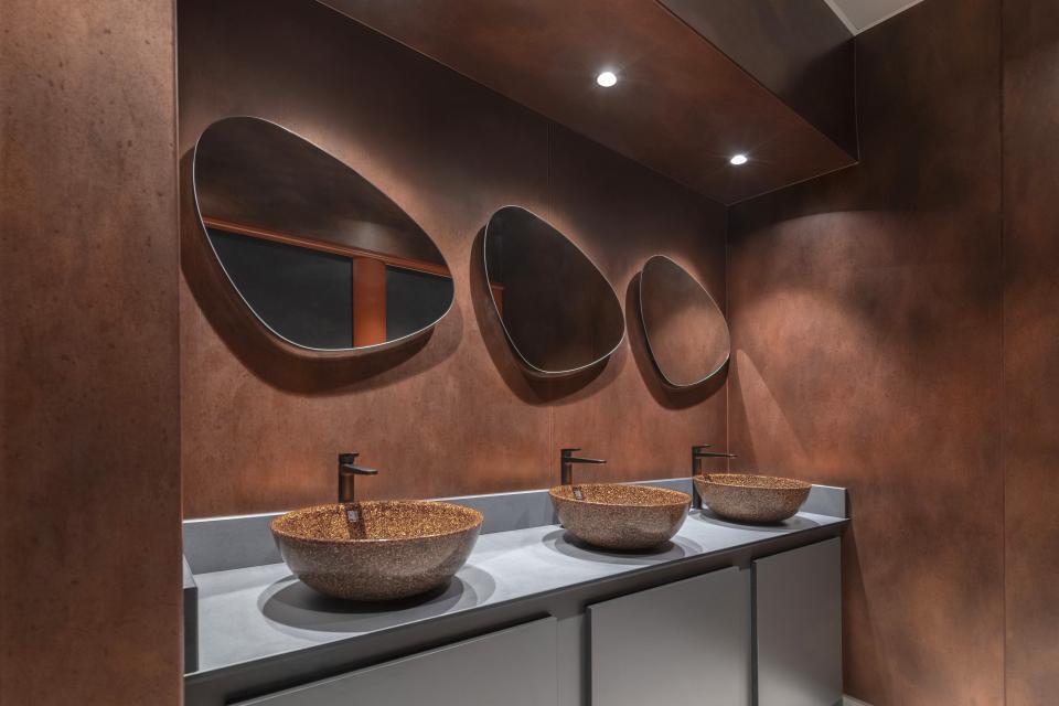 Elegant washroom featuring three unique bowls, stylish mirrors, and a warm copper backdrop at Material Source Studio Glasgow.