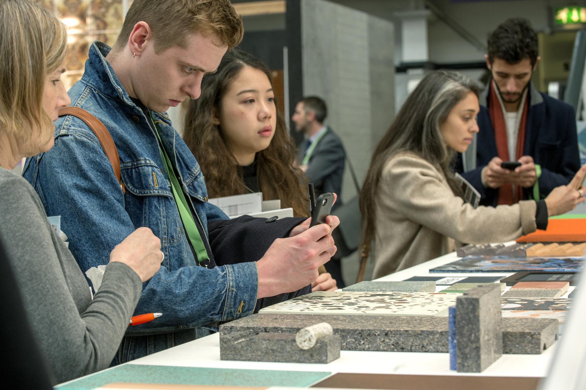 Visitors exploring innovative surface designs at the Surface Design Show 2020 in London, engaged with various materials.