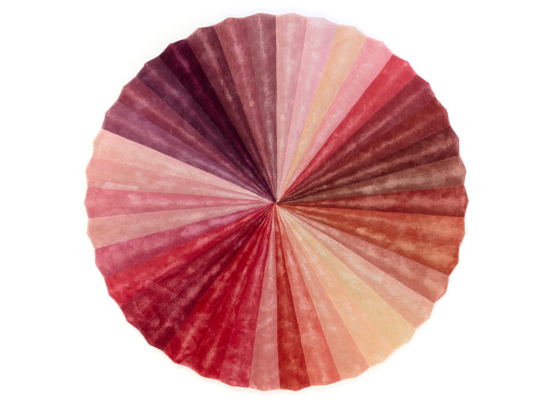 Colorful circular textile design featuring a gradient of pink and red tones, showcasing Kitty Joseph's innovative collaboration with FLOOR_STORY.