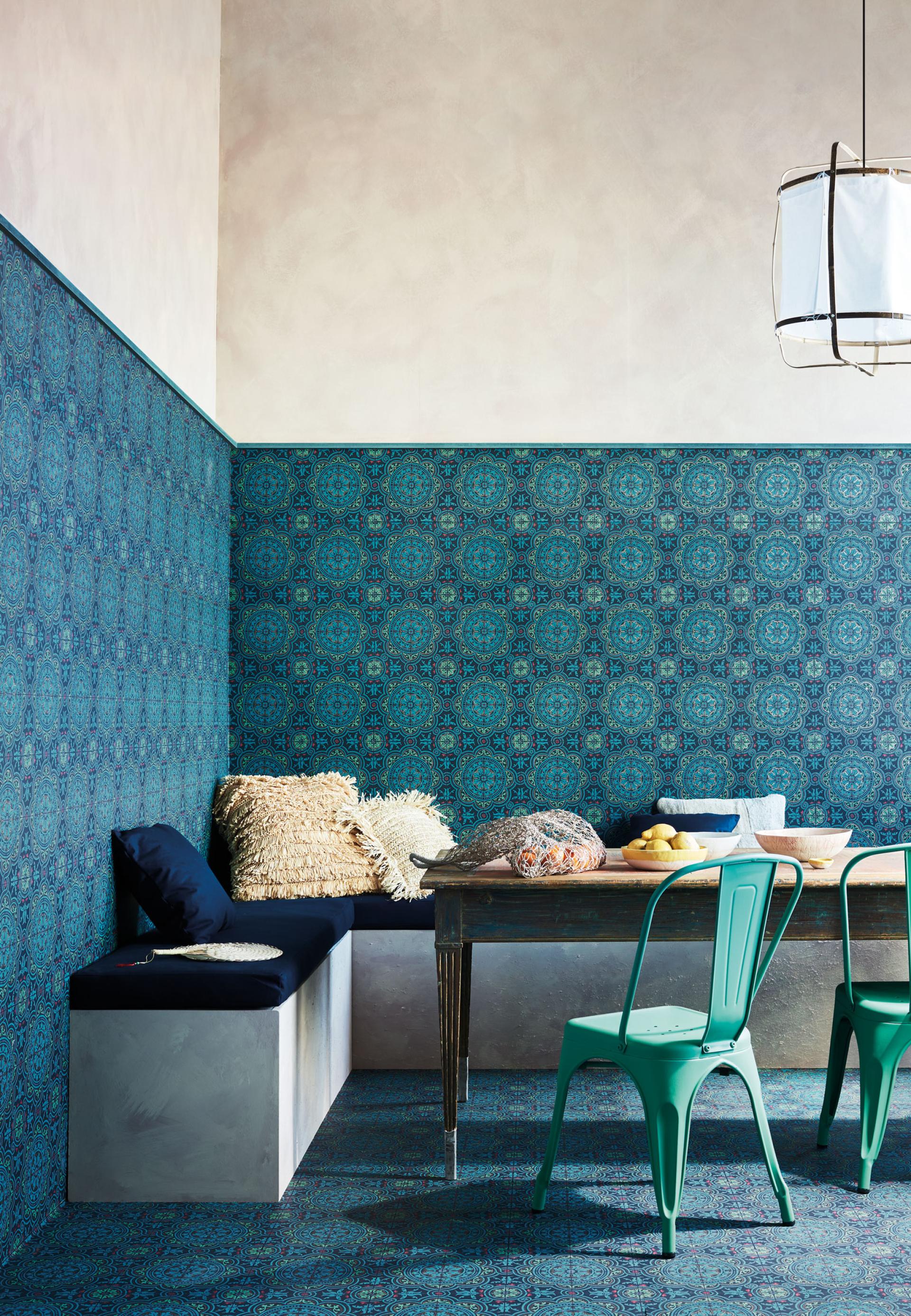 Vibrant blue patterned wallpaper adorns a cozy dining nook with stylish seating, wooden table, and decorative details.